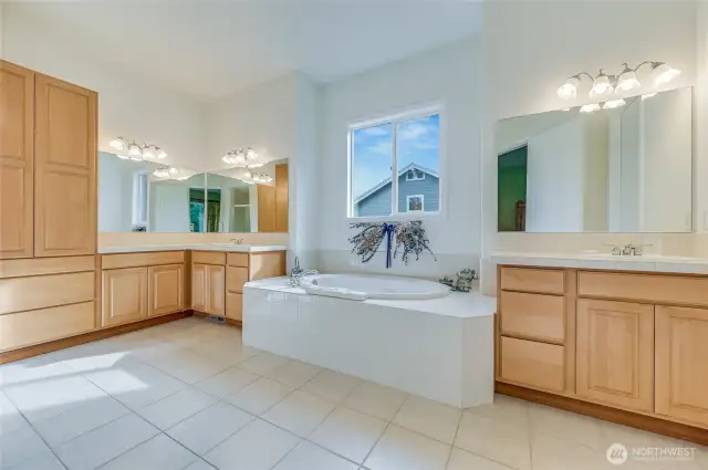 Primary bath with dual vanities + a linen cupboard.