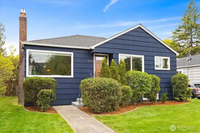 A deep navy facade, crisp white trim, and mature landscaping frame this classic West Seattle charmer.