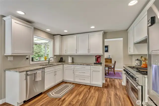 Stainless steel appliances including a Wolf 6-burner double oven range and white cabinetry add to the appeal of this kitchen.