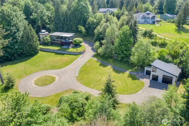 Aerial view of home, shop, grounds, wide driveways. Lots of parking for vehicles and recreation space for children, pets and guests.