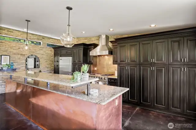 Beautiful Chef's kitchen with dark cabinets, granite countertops, copper wainscot, copper farm sink, and Viking appliances.