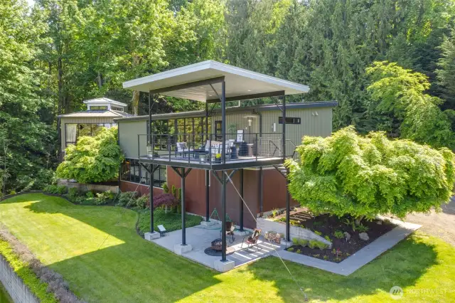 View of the rear side of the home. Beautiful clean lines. Covered patio plus covered deck off kitchen. Extensive plant beds and landscaping.