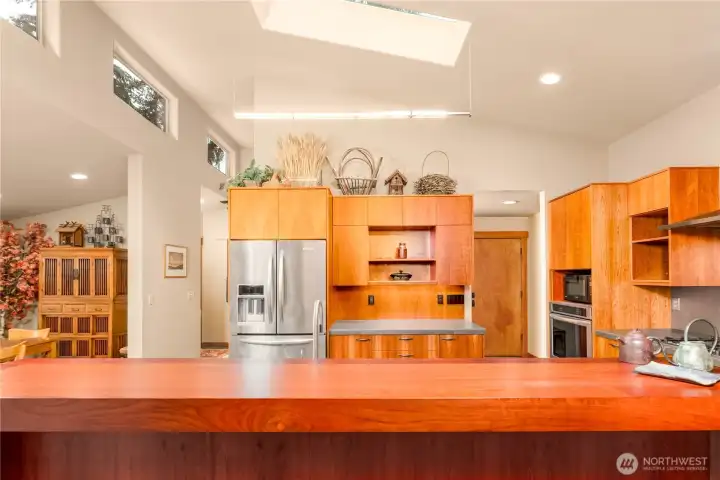 A contemorary kitchen, that relies on natural materials, incorporating steel, stone, grained wood tones with a neutral color palette.