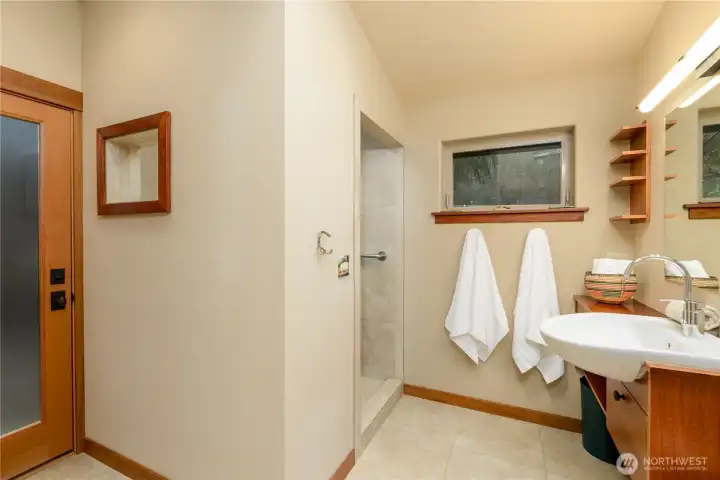 The executive bath ensuite is a spa-inspired retreat defined by clean lines and subtle Japanese design influence, featuring a walk-in shower, calming finishes, and a private connection to the outdoor veranda for moments of quiet restoration.