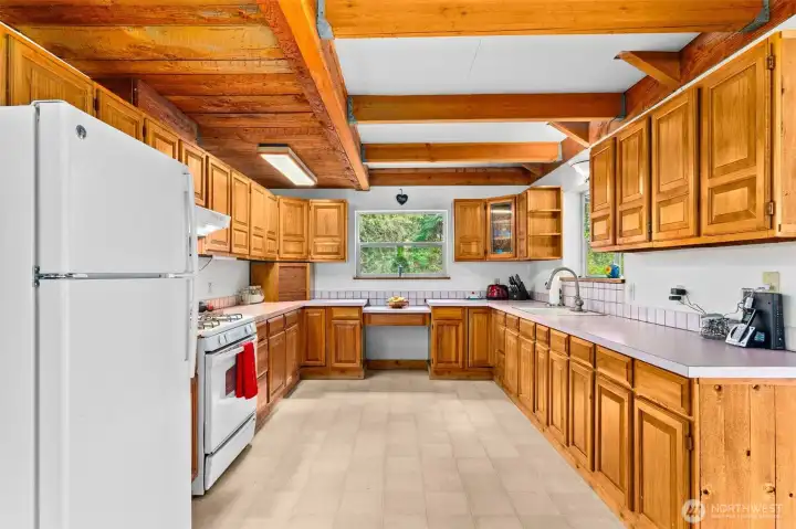 Kitchen with electric refrigerator, gas stove and plenty of cupboards and counter space.