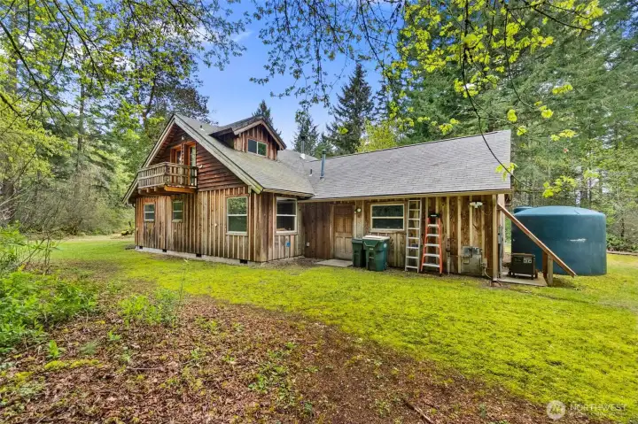 Back side of home with view of the garage and additional 2500 gallon water tank, and back up generator.