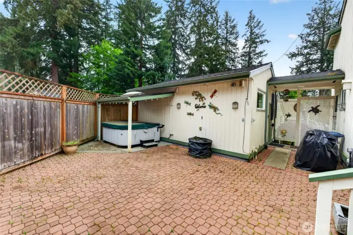 Enclosed back patio with a covered hot tub and access to the garages