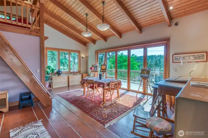 Large main room on the lower level in the studio. Folding glass doors open up to the deck on the west side of the structure. Ladder style stairs to upper loft area.