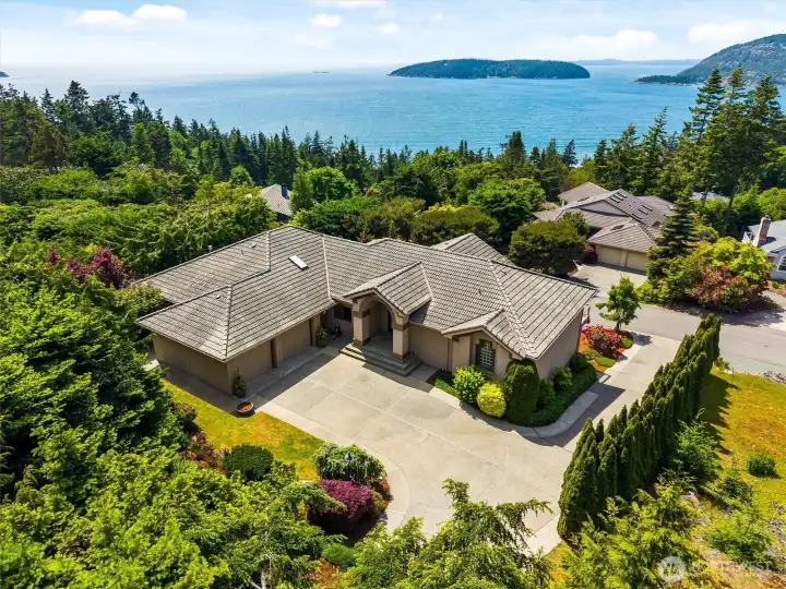 Aerial view showcasing the home's private setting, beautifully landscaped grounds, and sweeping views of the San Juan Islands and surrounding waterways.