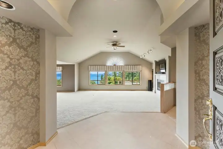 Welcoming entry opens to a spacious great room with vaulted ceilings, gas fireplace, and sweeping views of the San Juan Islands, water, and Olympic Mountains.