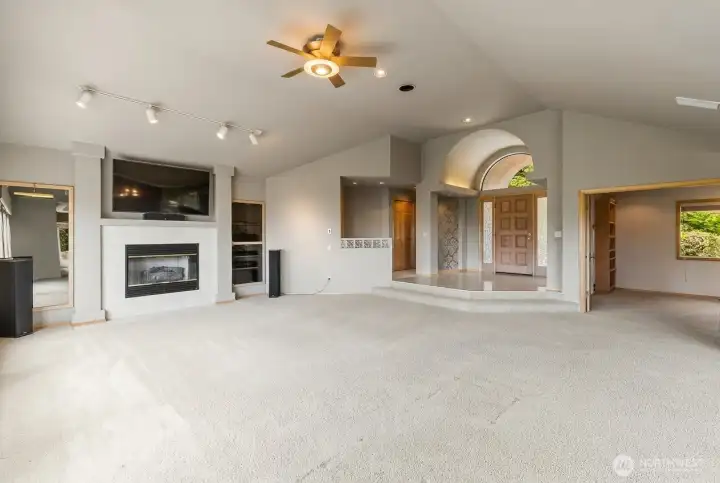 Spacious living room featuring vaulted ceilings, a gas fireplace, built-in surround sound, and an open layout designed for comfortable everyday living and entertaining.