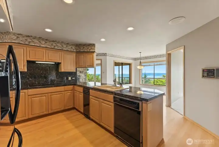 Kitchen with granite countertops, induction cooktop, generous cabinetry, and seamless flow to the breakfast nook, where water and island views become part of everyday living.