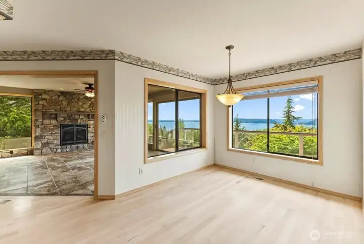 Breakfast nook with multiple windows framing the surrounding scenery, white oak flooring, and a light-filled setting for casual dining.