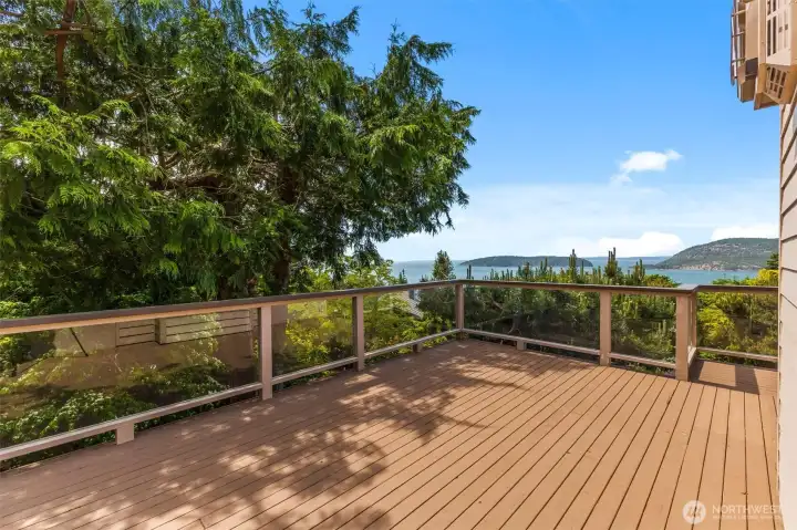 Private view deck with glass railings, generous space for outdoor furniture, and panoramic views of the San Juan Islands and surrounding waterways.