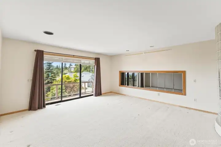 Generously sized primary suite offering exceptional flexibility for furnishings, a seating area, or personal retreat space, complete with deck access and peaceful surroundings.