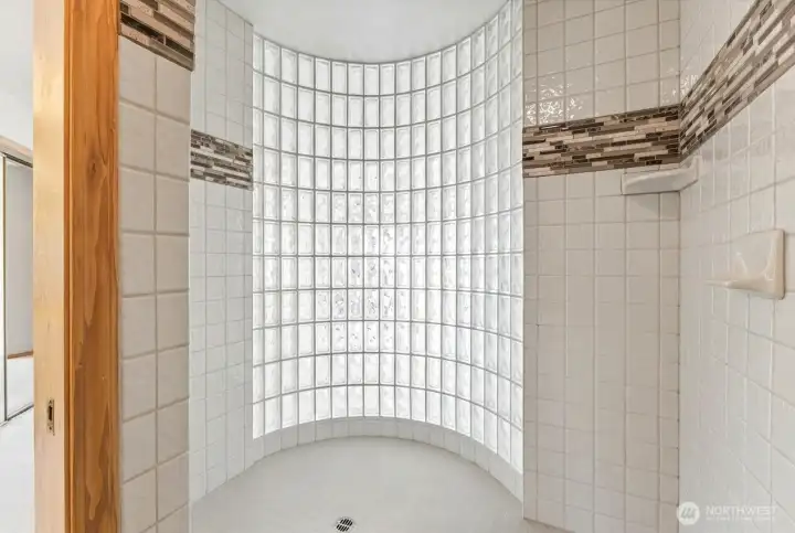 Oversized walk-in shower featuring a curved glass block wall that fills the space with natural light while maintaining privacy.