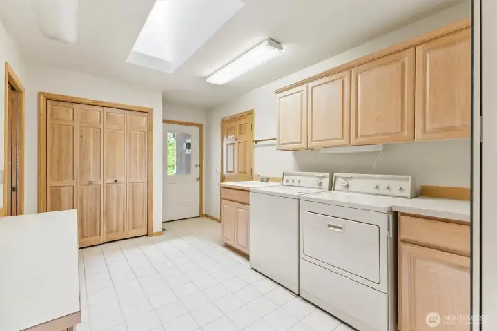 Designed for everyday functionality, this oversized laundry room includes extensive cabinetry, a utility sink, skylight, exterior access, and a generous storage closet that could easily double as a pantry.