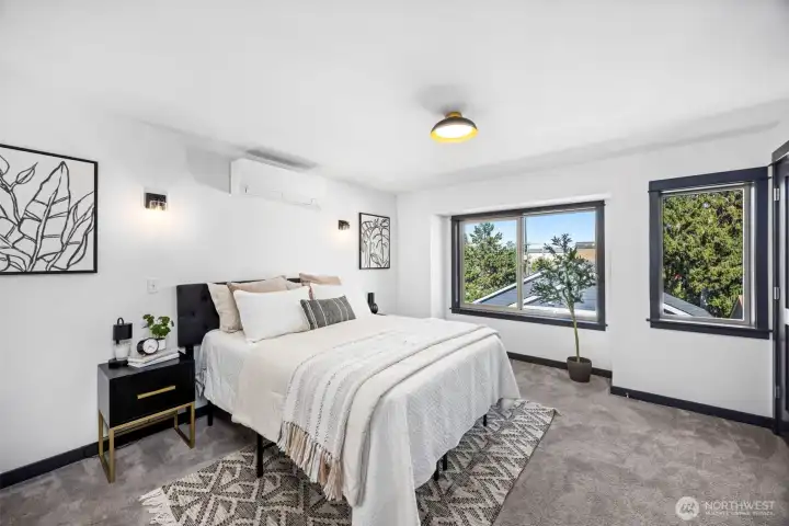 Peaceful primary bedroom features large windows with treetop views.