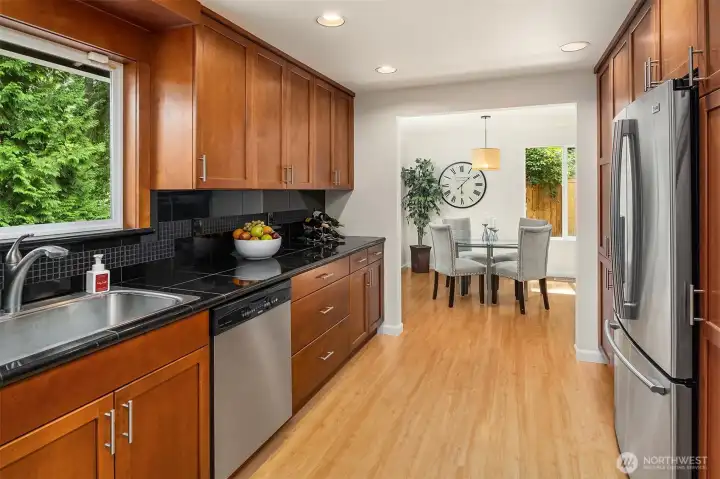 The large, renovated kitchen centers the living space ~ warm wood cabinetry, granite countertops with plenty of prep area, and adjacent dining room.