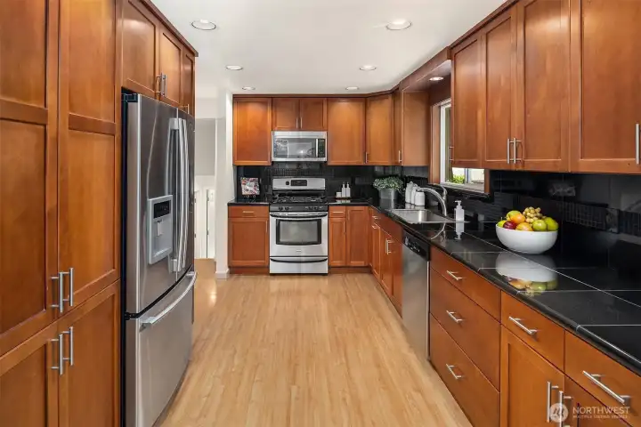 The large, renovated kitchen centers the living space ~ warm wood cabinetry, granite countertops with plenty of prep area, and adjacent dining room.