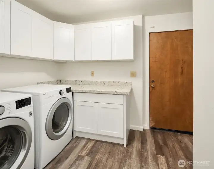 The large laundry room features new cabinets and granite counter.