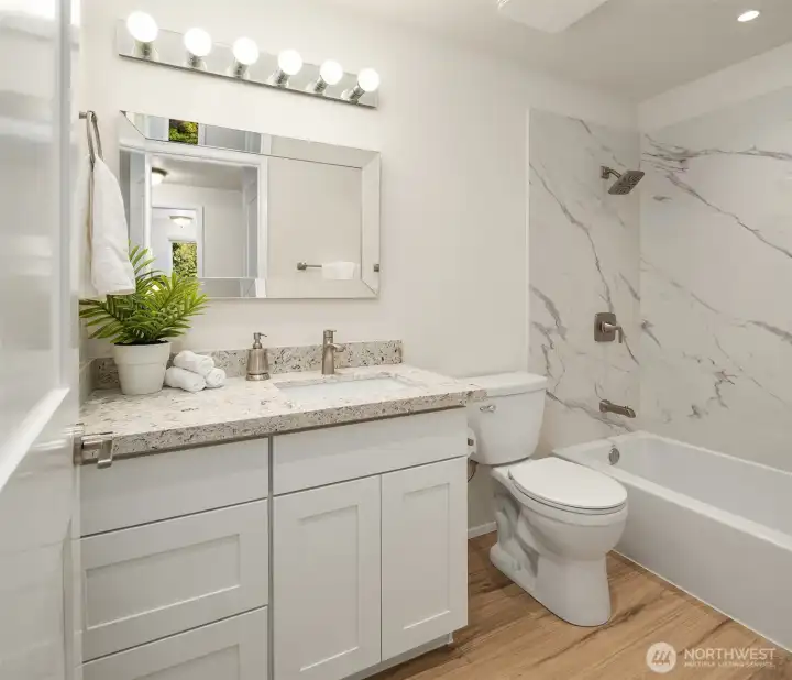 A fully-remodeled guests bath includes new cabinets, granite counter, fixtures, flooring, tub/shower and new upper-floor doors.