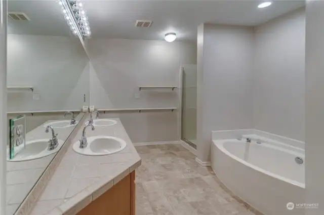 Large Primary Bathroom suite has dual sinks, over-sized soaking tub, toilet and dedicated shower.