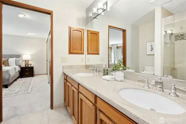 Another view of the primary bath with stone countertops and sleek undermount sinks