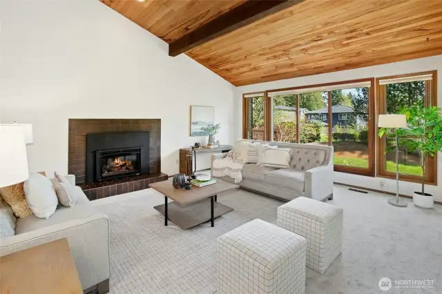 Living room with vaulted ceilings, a wall of windows, and an inviting gas fireplace