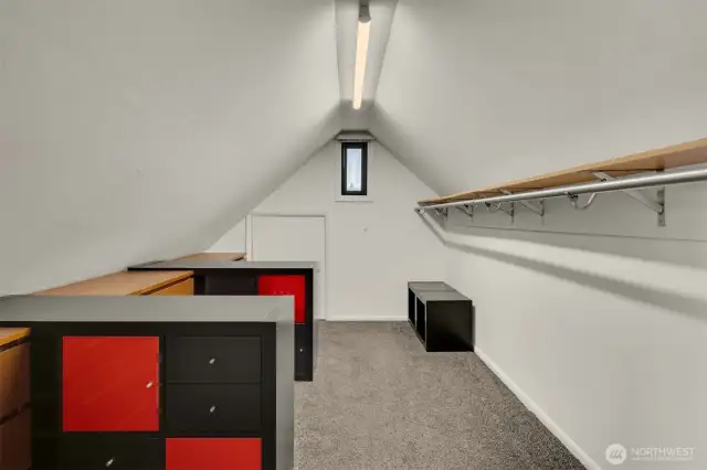 Walk-in closet with access to storage attic area behind the far door.