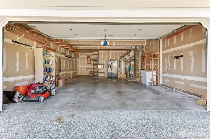 Large, oversized 2-car garage with bump out extra storage, drywalled / insulated. Includes additional stainless steel refrigerator & freezer, lawnmower and household paint/supplies for new owner.