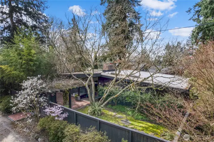 Midcentury modern home tucked into a quiet Mercer Island enclave, featuring clean architectural lines, mature landscaping, and a private corner lot setting. Fully fenced yard offers privacy and a park-like feel.