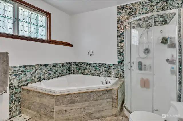 Primary bath with large jetted soaking tub and extensive accent tile work.