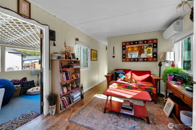 View from kitchen across living room to hallway to bedrooms and bathroom with front entry on left.