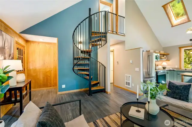 A solid steel spiral staircase leads to a spacious, light-filled second bedroom