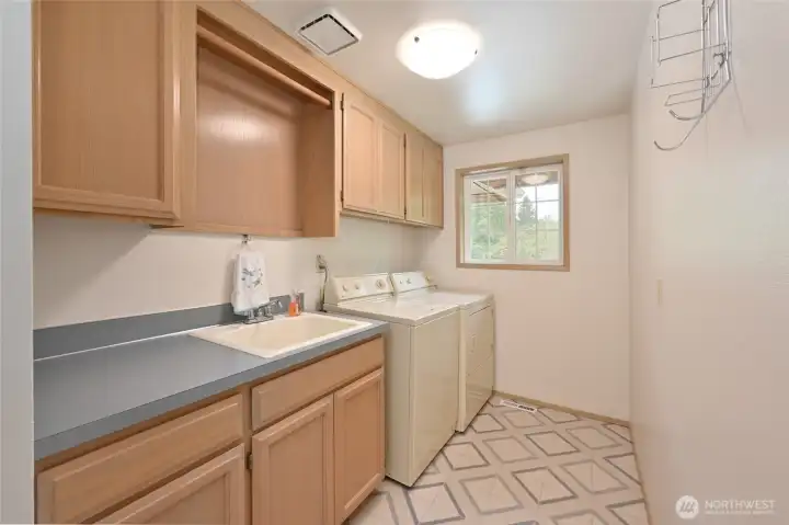 Laundry room next to garage door has utility sink, good storage, and full size W/D