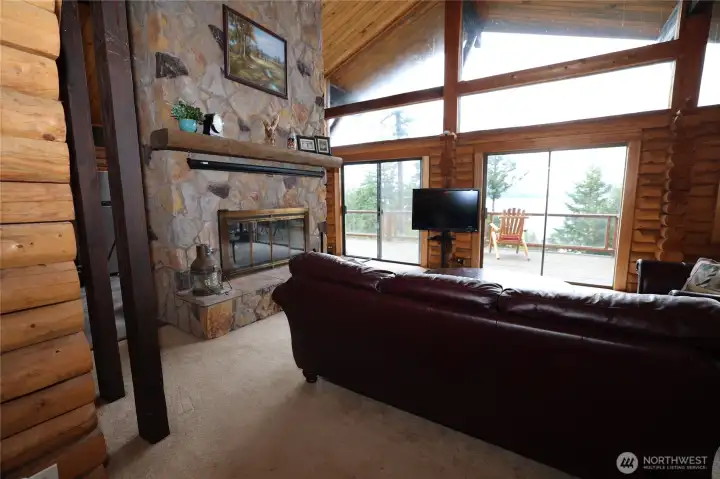 Upper-level living space with vaulted ceilings, exposed log construction, and large windows that frame the water views.