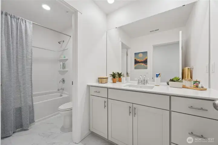 Secondary bathroom upstairs with door splitting the shower/toilet area from sink.  Quartz countertops. Soft close cabinets.  Pictures are for representational purposes only, colors and features may vary.