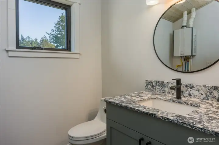 Half bath.  Propane on demand hot water heater is reflected in the mirror.