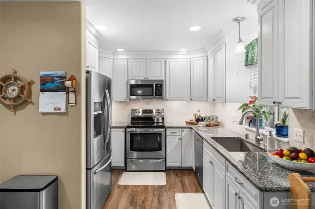 Tall cabinets with crown moulding give the kitchen extra style and storage!  New backsplash and stone counters set off this charming, convenient space !  Don't miss the pantry to the left of the kitchen.