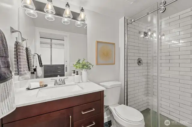 Bright and tailored, the en suite bath pairs polished tilework with streamlined fixtures and warm wood tones for a clean, modern finish.