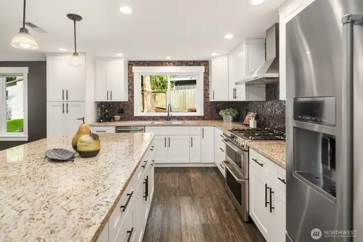 A stunning kitchen remodel with shaker cabinets, quiet-close drawers and pull-outs, granite countertops, stainless steel appliances, and a large eating island. GE dual oven and KitchenAid refrigerator.