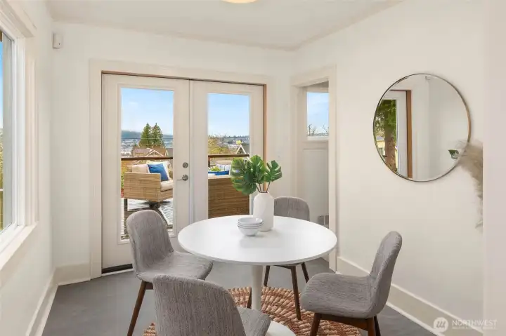 Casual eating area with French doors opening to the spacious deck with views on the Ship Canal & Olympic Mountains on a clear day.