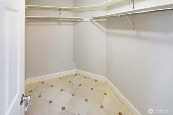 Spacious walk-in-closet featuring tile flooring to match the bathroom, and ample hanging storage for organized living.