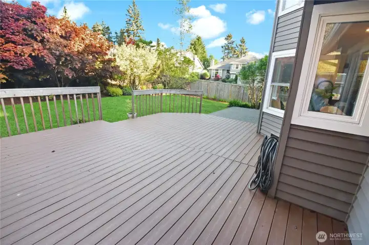 Spacious deck built of Trex decking for easy maintenance is perfect for outdoor gatherings, surrounded by vibrant landscaping and lush greenery.
