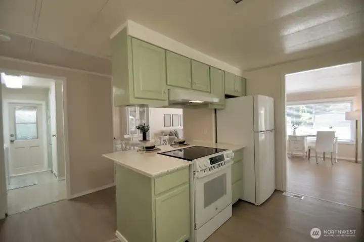Photo showing how the kitchen flows from the living and dining areas. To the left is the utility room with a door for backyard access. Photo showing how the kitchen flows from the living and dining areas. To the left is the utility room with a door for backyard access.