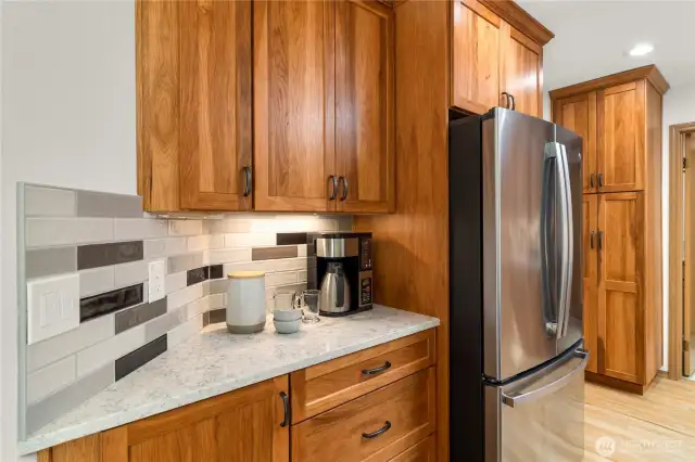 Beautiful bright kitchen with gorgeous Pecan cabinetry, stainless steel appliances, quartz counters and tile backsplash.