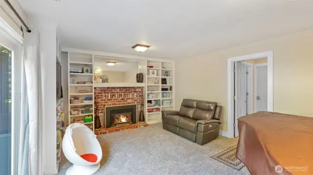 Cozy up by the gas fireplace framed by custom built-in bookshelves. To the side, doors lead to additional rooms including a bathroom, laundry area, and versatile extra space