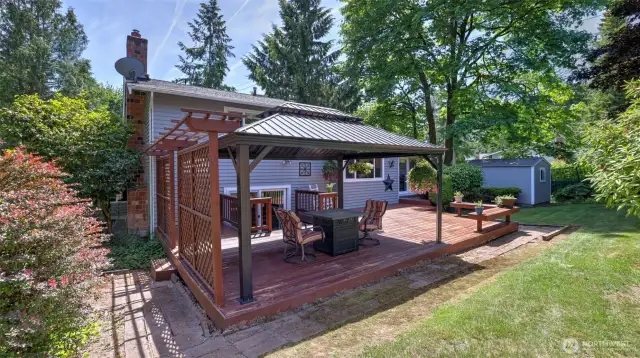 Along this warm-toned wooden porch, the backyard features a convenient shed—perfect for storing tools, garden supplies, and more