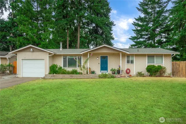 A look at the welcoming front entrance reveals the home's charming exterior, covered porch, and bold blue front door. Thoughtful landscaping lines the entry path, while the neutral siding and fresh trim provide a clean, well-maintained first impression.